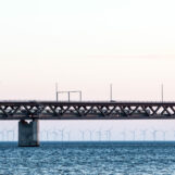 A beautiful shot of the Oresund Bridge over the water with windmills in the distance